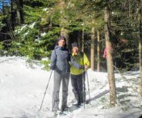 two women wearing snowshoes in the woods