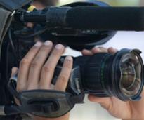 closeup of hands holding a large video camera 