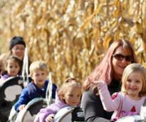 moms and kids on tiny train ride by corn field