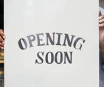 hands holding up opening soon sign