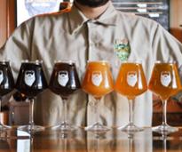 closeup of man standing behind a bunch of artisanal brew works beers