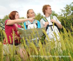three people hiking through a field