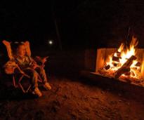 kid sits by campfire at night