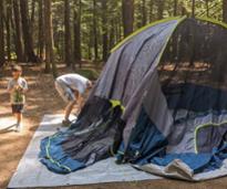 man sets up camping tent, kid nearby