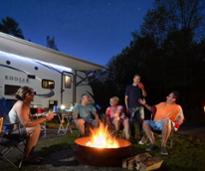 campers sit around campfire by rv