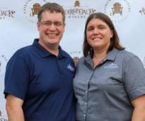 couple poses in front of adirondack winery background