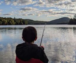 back of a kid fishing at a lake