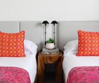 two beds and nightstand in modern hotel room