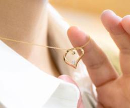 woman holding up a heart necklace