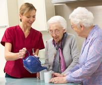 aide pouring tea for two older women