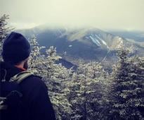 man admiring the view from a mountain summit in winter