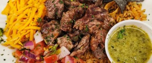 steak, rice, cheese dish with green sauce on the side