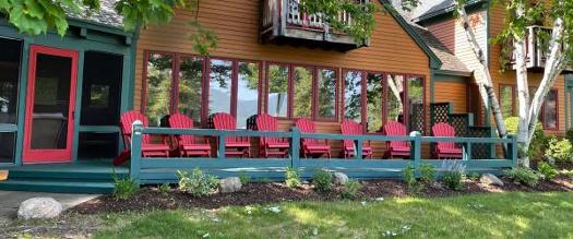 lake george vacation rental with many adirondack chairs on the front porch