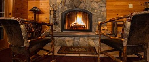 two chairs by fire in fireplace in cabin