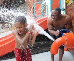 father and son playing in an indoor water park