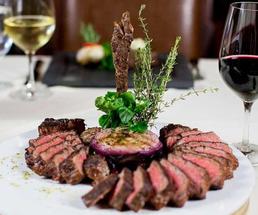 steak dinner on plate near wine glasses