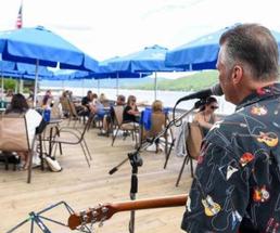 man sings on restaurant deck with guitar