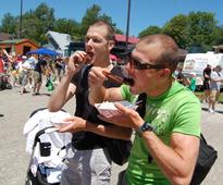 two guys eating barbecue food at a festival