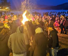 people gathering around bonfire on the beach at lake george winter carnival