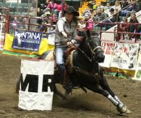 woman riding a horse in a barrel racing event