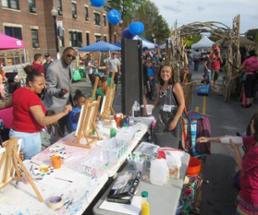 people by a table at an outdoor street fair