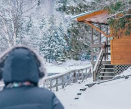 the back of a person approaching a cabin in the winter