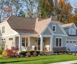 a residential house with a garage and fall colors on trees