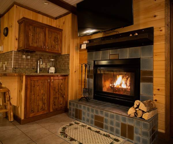 fire in fireplace in cabin kitchen with tv mounted above
