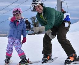 dad and daughter downhill skiing pose for photo