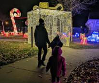 dad and kids walk by lit up present display at winter realms