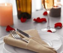 rose petals by a plate with silverware and glasses