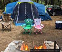 campsite with tent, kids chairs, fire in fire pit