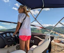 woman drives a boat on lake george