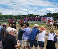 people standing by fence at a horse race track