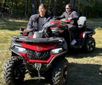 two people riding on red and black ATVs