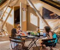 three kids eat in front of a glamping tent