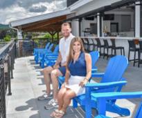 katie and will carson on blue adirondack chairs on restaurant deck