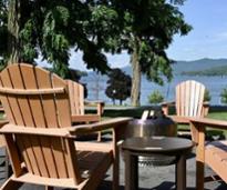 Adirondack Chairs surrounding a firepit with a lake in the background