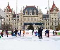 people ice skating outdoors near a city building