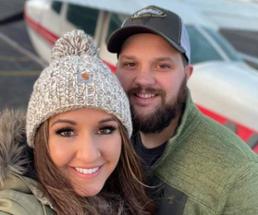 couple in front of small plane