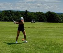 woman swings golf club on golf course