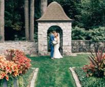 bride and groom kissing in front of a stone arch in a wall