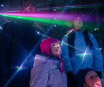 family bundled up for winter looks up at dazzling lights