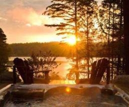 A pair of Adirondack chairs at Fern Lodge look out over a sunset on Friends Lake.
