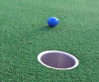 blue golf ball rolling toward the cup