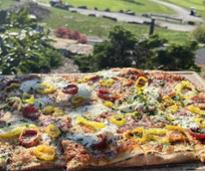 flatbread pizza held up against backdrop of golf course