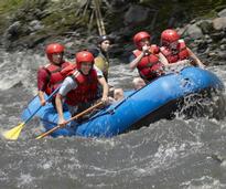 people in red helmets whitewater rafting in a blue raft
