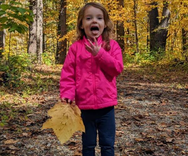 little girl holding up a fall leaf