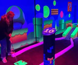 woman playing glow in the dark indoor mini golf