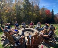 people sit around a fire pit in the fall